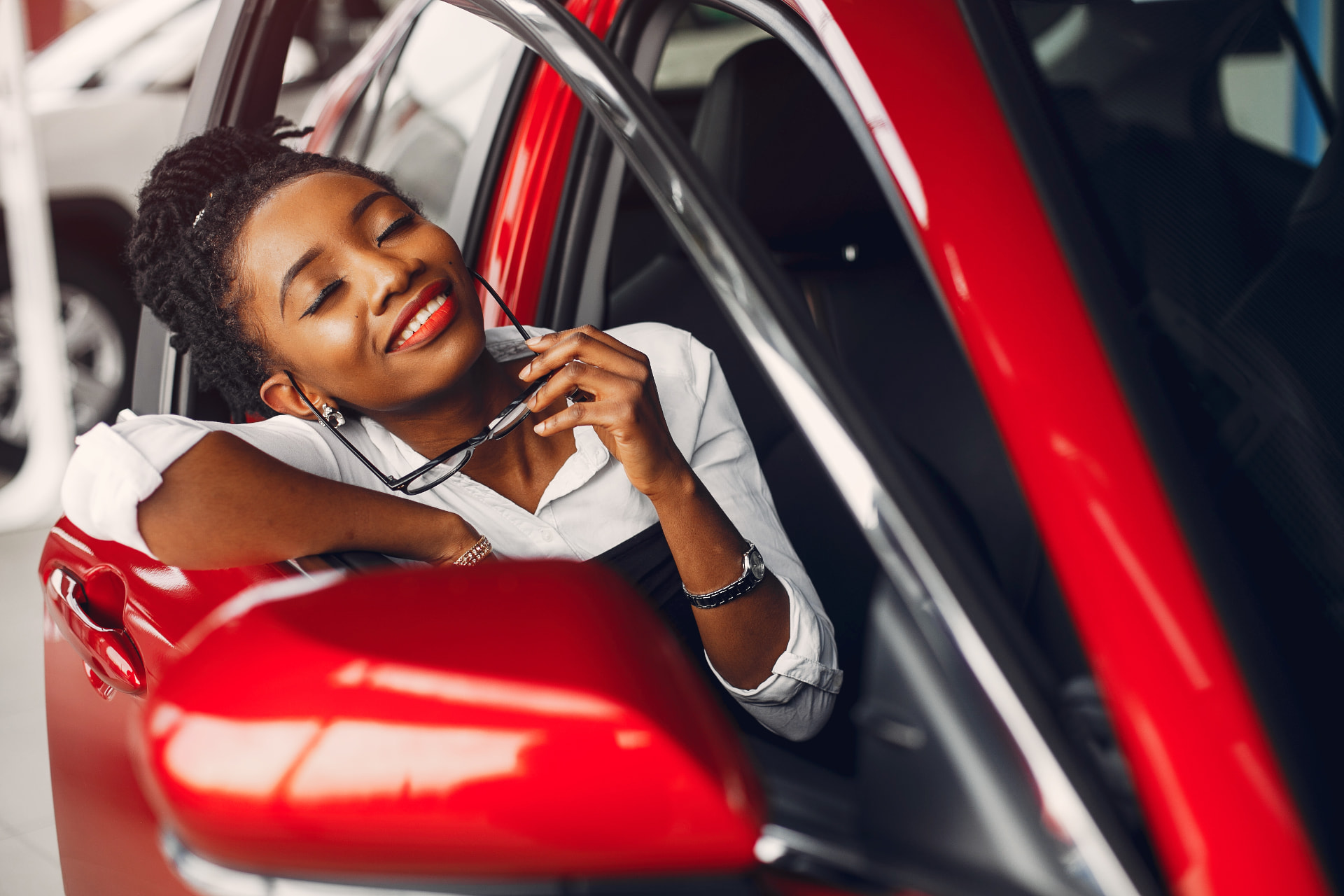 Smiling car owner leaning out of her red car window